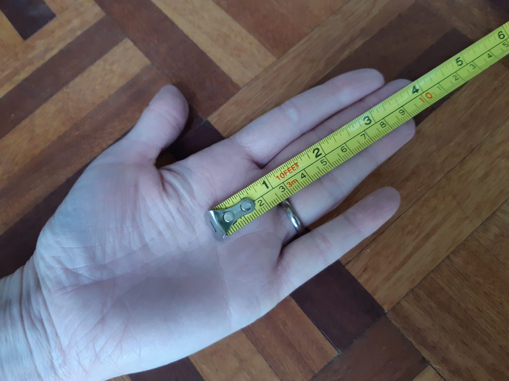 A photo of a hand with a tape measure to show the distance from fingertip to lateral palm crease - helpful for sizing tennis racquet grips